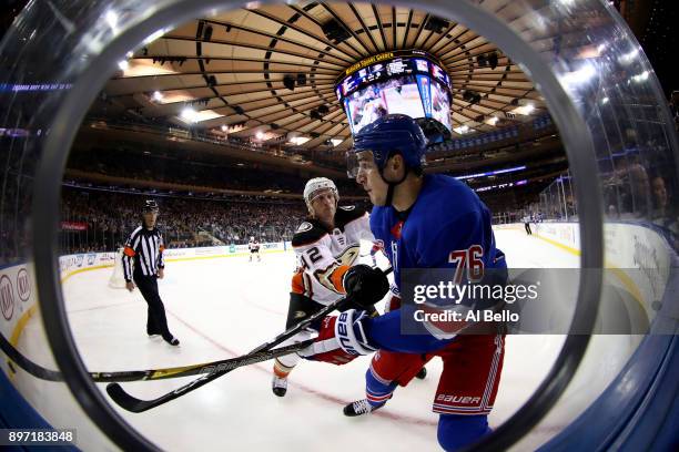Brady Skjei of the New York Rangers is checked by Josh Manson of the Anaheim Ducks dduring their game at Madison Square Garden on December 19, 2017...