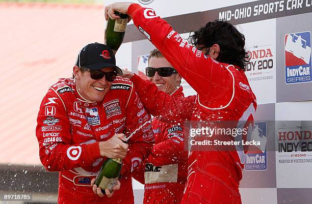 Third place Ryan Briscoe, driver of the Dallara Honda, watches as Second place Dario Franchitti pours champagne on teammate and champion Scott Dixon,...