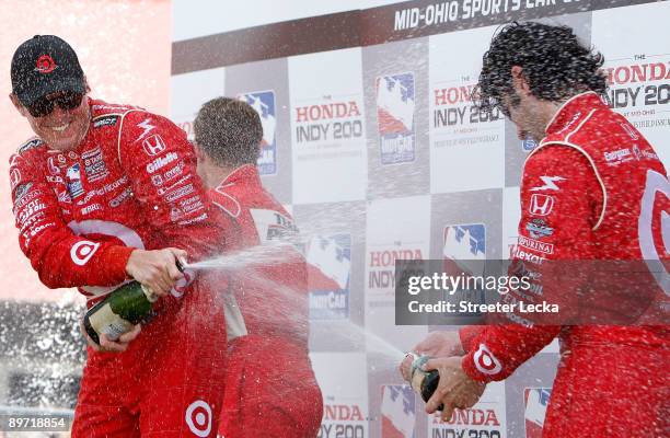 Third place Ryan Briscoe, driver of the Dallara Honda, watches as Second place Dario Franchitti pours champagne on teammate and champion Scott Dixon,...