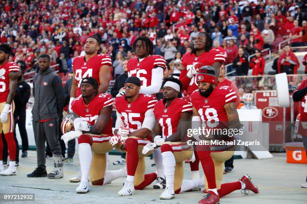 Eli Harold, Eric Reid, Marquise Goodwin and Louis Murphy of the San Francisco 49ers kneel on the sideline during the anthem as Solomon Thomas, Reuben...