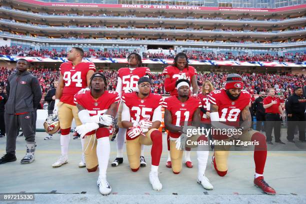 Eli Harold, Eric Reid, Marquise Goodwin and Louis Murphy of the San Francisco 49ers kneel on the sideline during the anthem as Solomon Thomas, Reuben...