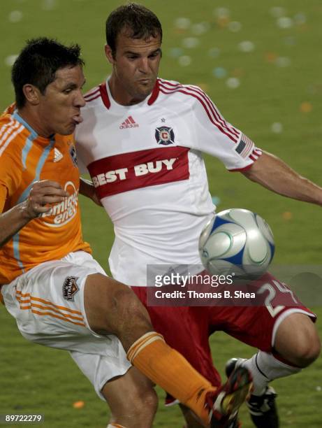 Brian Ching of the Houston Dynamo challenges Daniel Woolard of the Chicago Fire at Robertson Stadium on August 9, 2009 in Houston, Texas.