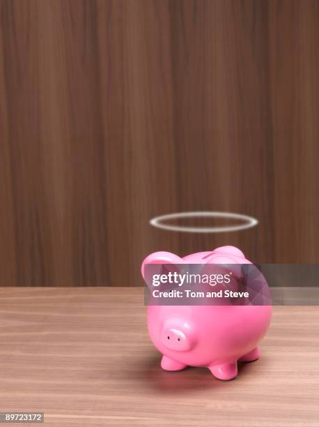 piggybank with halo in office. - saving for a rainy day englische redewendung stock-fotos und bilder