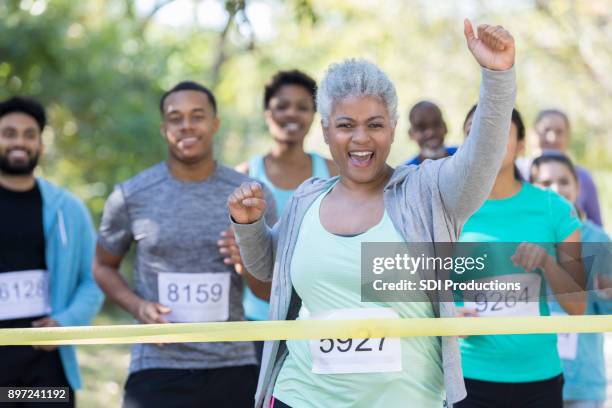 senior woman is first to cross finish line in charity race - finish line ribbon stock pictures, royalty-free photos & images