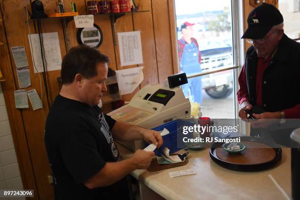 Tony Amidei, left, owner of George's Drive-Inn Burgers, a restaurant in Walsenburg that his father started 40 years ago, closes a customer's tab on...