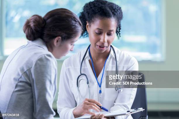 doctor reviews a patient's medical information - health insurance stock pictures, royalty-free photos & images