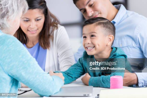 nurse examines boy in community free clinic - father and children volunteering stock pictures, royalty-free photos & images