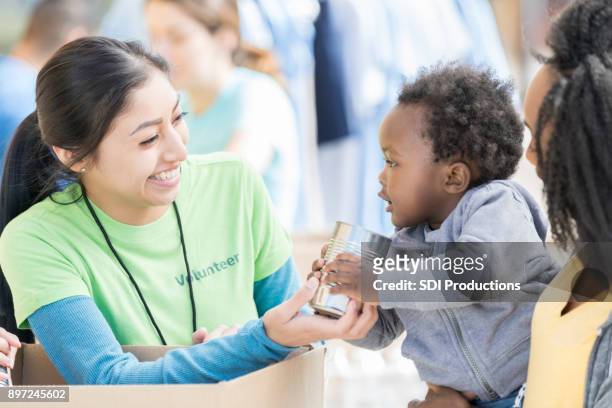 adorabile bambino dà cibo in scatola al volontario della banca del cibo - pianificazione di emergenza foto e immagini stock