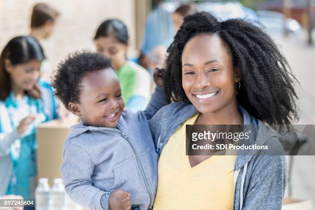 beautiful mom and her baby boy during charity food drive - emergency preparation stock pictures, royalty-free photos & images