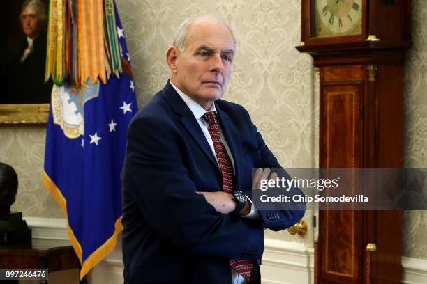 White House Chief of Staff John Kelly stands behind journalists as U.S. President Donald Trump signs the tax reform bill into law in the Oval Office...