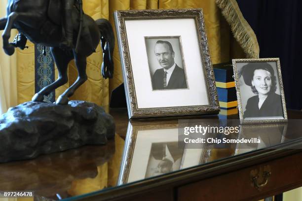 Photographs of U.S. President Donald Trump's parents stand on the table behind his desk as he signs the tax reform bill into law in the Oval Office...