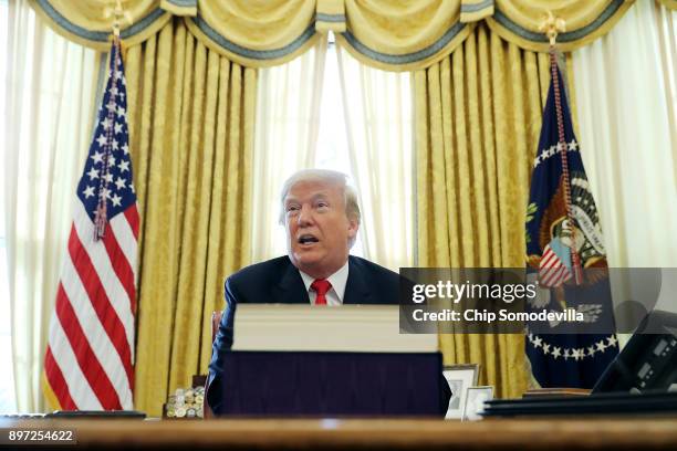 President Donald Trump talks with journalists after signing tax reform legislation into law in the Oval Office December 22, 2017 in Washington, DC....