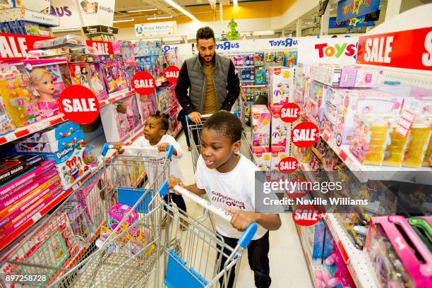 Aston Villa's Neil Taylor join the Hayden family from Kingstanding, Birmingham on a 'Supermarket Sweep' at the Toys 'R' Us Store on December 20, 2017...