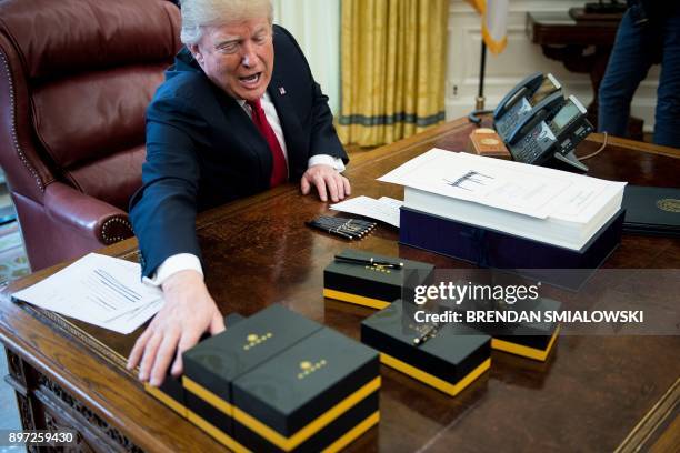 President Donald Trump offers pens to the press after signing a tax reform bill in the Oval Office of the White House December 22, 2017 in...