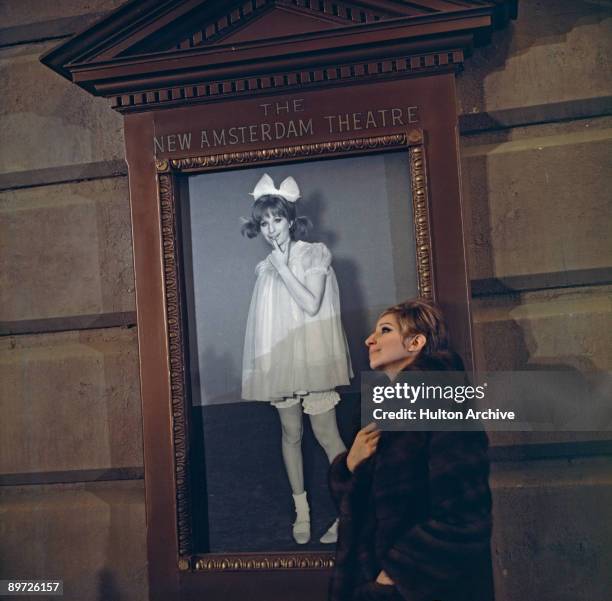 American actress and singer Barbra Streisand outside the New Amsterdam Theatre, New York, with a poster of herself in the movie 'Funny Girl', 1968.