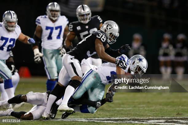 Alfred Morris of the Dallas Cowboys is tackled by Reggie Nelson and TJ Carrie of the Oakland Raiders at Oakland-Alameda County Coliseum on December...