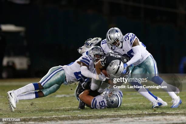 DeAndré Washington of the Oakland Raiders is tackled by Sean Lee, Xavier Woods and Anthony Brown of the Dallas Cowboys at Oakland-Alameda County...