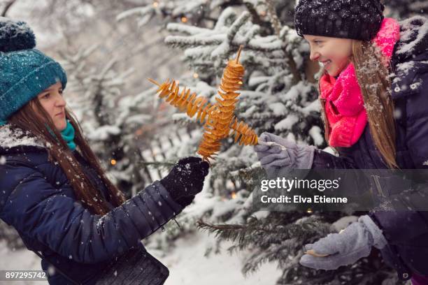 two children pretending to duel with spiralised potato chips at a german christmas market - family eating potato chips imagens e fotografias de stock