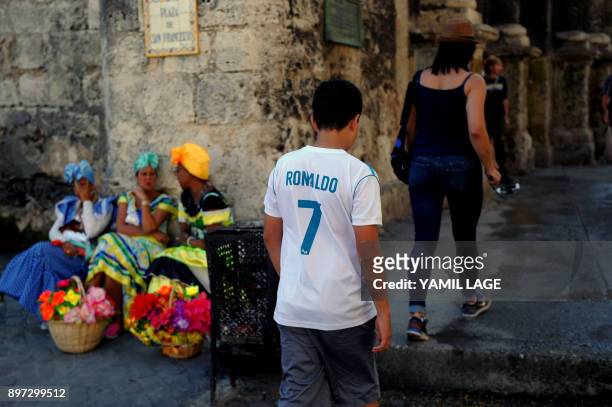 Cuban wearing a jersey of Spain's football team Real Madrid walks along the street in Havana on the eve of huge El Clasico clash against Barcelona,...