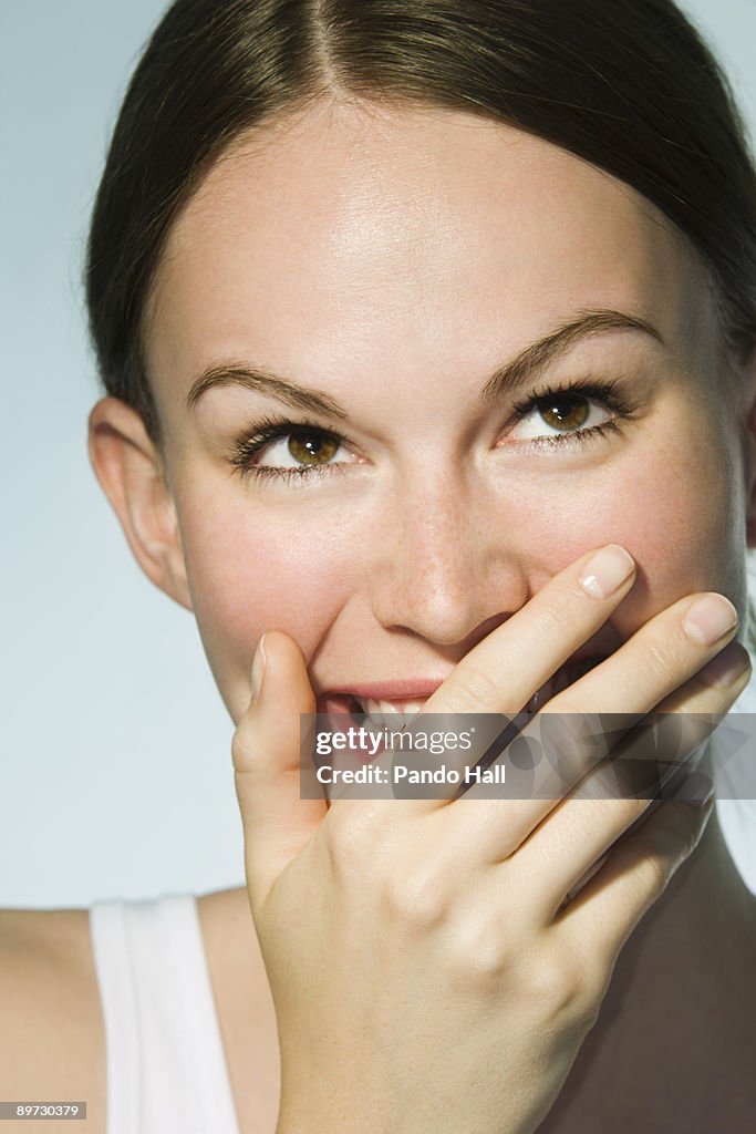 Young woman laughing, hands in front of mouth