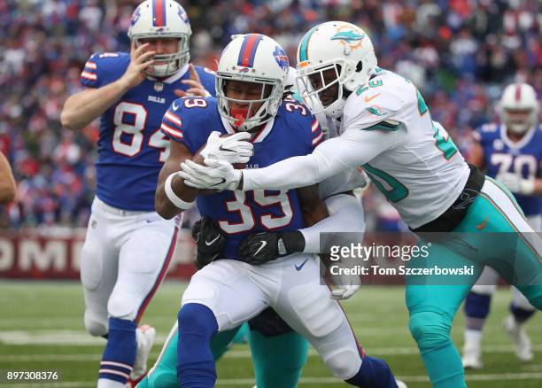 Travaris Cadet of the Buffalo Bills runs with the ball as he is tackled by Reshad Jones of the Miami Dolphins during NFL game action at New Era Field...