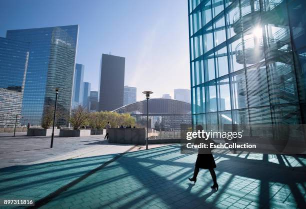 businesswoman walking towards center of business district - business city stock-fotos und bilder