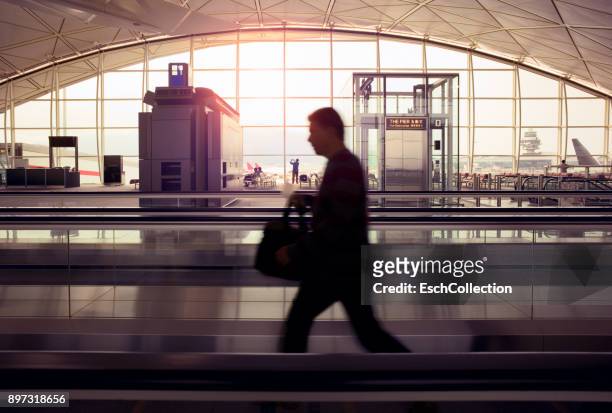 businessman on moving escalator at modern airport - hong kong international airport stock pictures, royalty-free photos & images