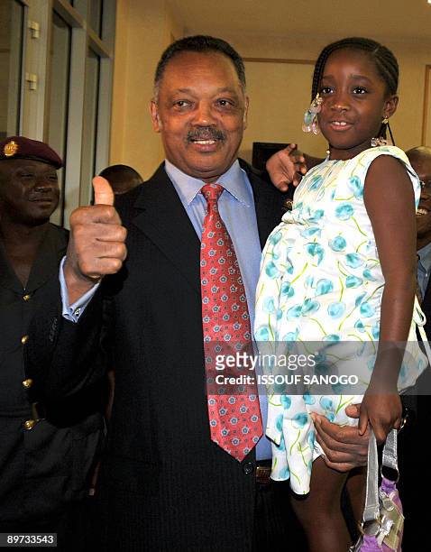 Reverend Jesse Jackson gives a thumbs up as he poses with Obre, one of the grand children of Ivory Coast President Laurent Gbagbo at the presidential...