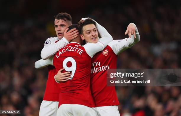 Mesut Ozil of Arsenal celebrates as he scores their third goal with Granit Xhaka and Alexandre Lacazette during the Premier League match between...
