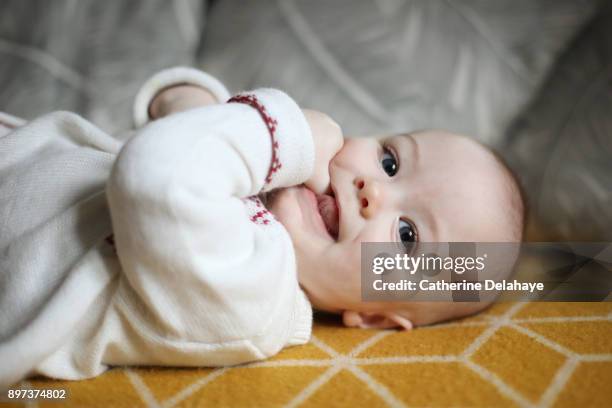 a 6 months old baby boy laying on a sofa - 6 11 maanden stockfoto's en -beelden