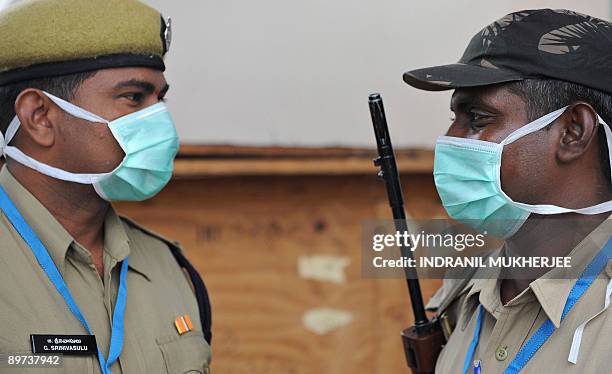 Indian policemen wearing protective masks interact as they keep watch at the player's entrance gate of the Gachibowli Stadium during the ongoing...