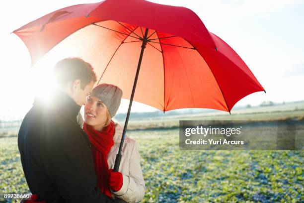 portrait of happy young couple sharing a red umbre - 18 23 months stock pictures, royalty-free photos & images