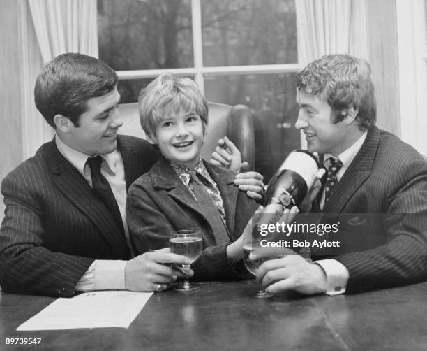 English child actor Mark Lester pours champagne for boxing champion Johnny Cheshire, who is signing a contract with manager John Daly, 28th November...