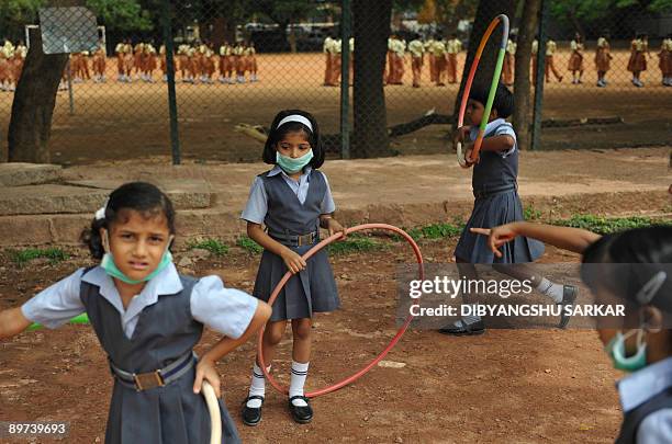 Indian schoolchildren wearing protective masks play outside a school in Bangalore on August 11, 2009. The number of people to die from swine flu in...