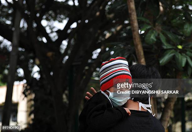 An Indian child wearing a mask takes rest on his father's shoulder as they queue outside an H1N1 swine flu virus test centre at a government hospital...