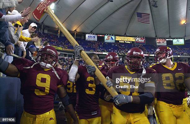 Wide receivers Pierre Jackson, Ron Johnson and Ben Utecht help center Akeem Akinwale of the Minnesota Golden Gophers celebrate with Paul Bunyan's...