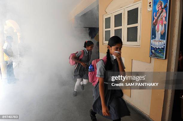 Indian school students run for cover as health workers from Ahmedabad Municipal Corporation fumigate K. R. Raval Primary school in Ahmedabad on...