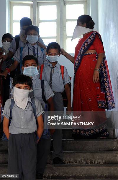 An Indian teacher supervises a class of mask wearing children at K. R. Raval Primary school in Ahmedabad on August 11 as the swine flu death total...