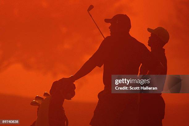 Tiger Woods hits a shot as his caddie Steve Williams looks on during the second preview day of the 91st PGA Championship at Hazeltine Golf Club on...