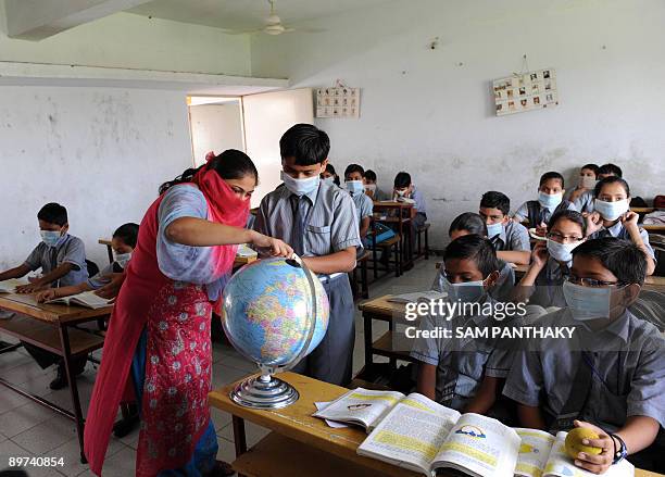 An Indian teacher takes a class of mask wearing children at K. R. Raval Primary school in Ahmedabad on August 11 as the swine flu death total rose in...