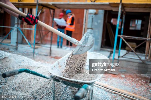 shovelling on construction site - wheelbarrow stock pictures, royalty-free photos & images