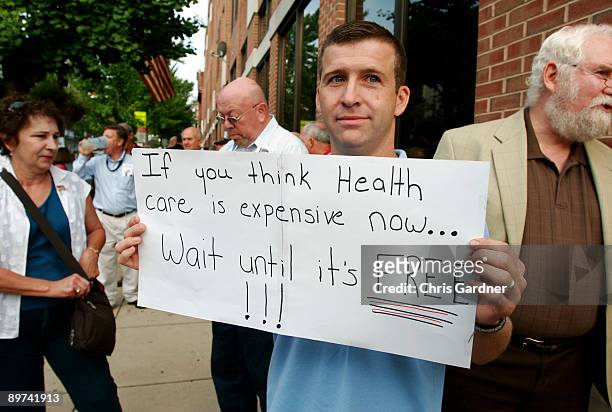 Sam Abram of Lebanon, Pennsylvania, holds a sign in protest as he waits to attend a town hall meeting held by U.S. Sen. Arlen Specter August 11, 2009...