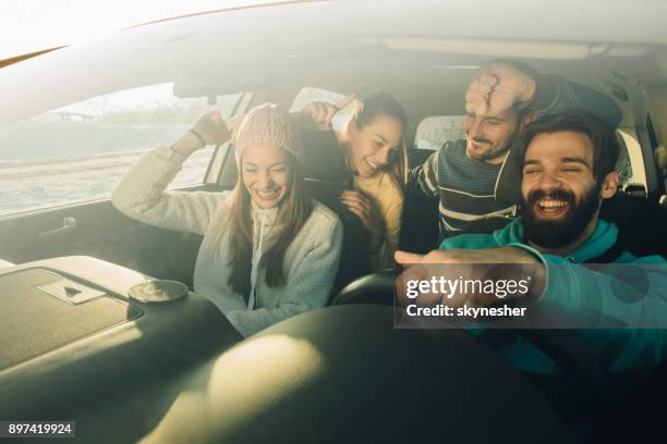 grupo de amigos felices divirtiéndose bailando durante un viaje por carretera en el coche. - four people in car fotografías e imágenes de stock