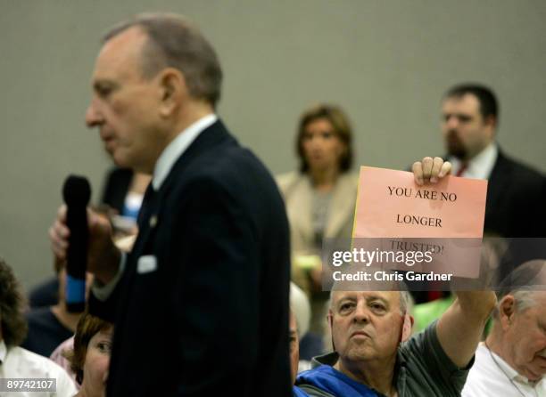 Tom Davis of Lebanon, Pennsylvania, holds a sign as U.S. Sen. Arlen Specter speaks during a town hall meeting August 11, 2009 in Lebanon,...