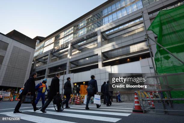 Pedestrians cross a road past the construction site for magnetic levitation train tracks and platforms at Shinagawa Station in Tokyo, Japan, on...