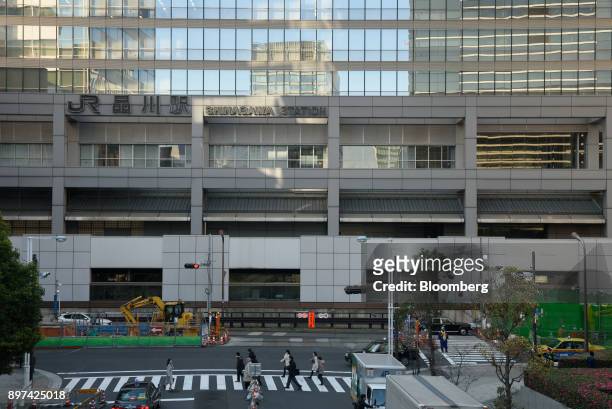 Pedestrians cross a road past the construction site for magnetic levitation train tracks and platforms at Shinagawa Station in Tokyo, Japan, on...