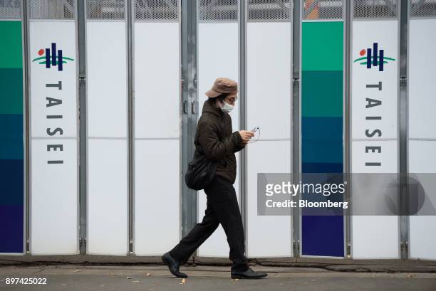 Pedestrian walks past the Taisei Corp. Logos displayed on a fence at a construction site in Tokyo, Japan, on Friday, Dec. 22, 2017. Japan's major...