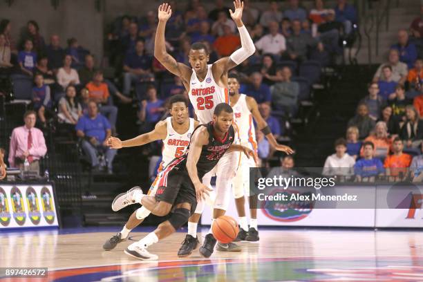Shawn Johnson of the Incarnate Word Cardinals dribbles past KeVaughn Allen and Keith Stone of the Florida Gators during a NCAA basketball game at the...