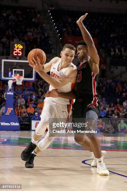 Egor Koulechov of the Florida Gators drives past Jorden Kite of the Incarnate Word Cardinals during a NCAA basketball game at the Stephen C. O'...