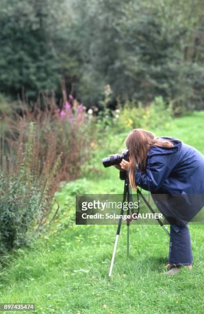 Jeune fille photographiant des plantes dans un jardin.